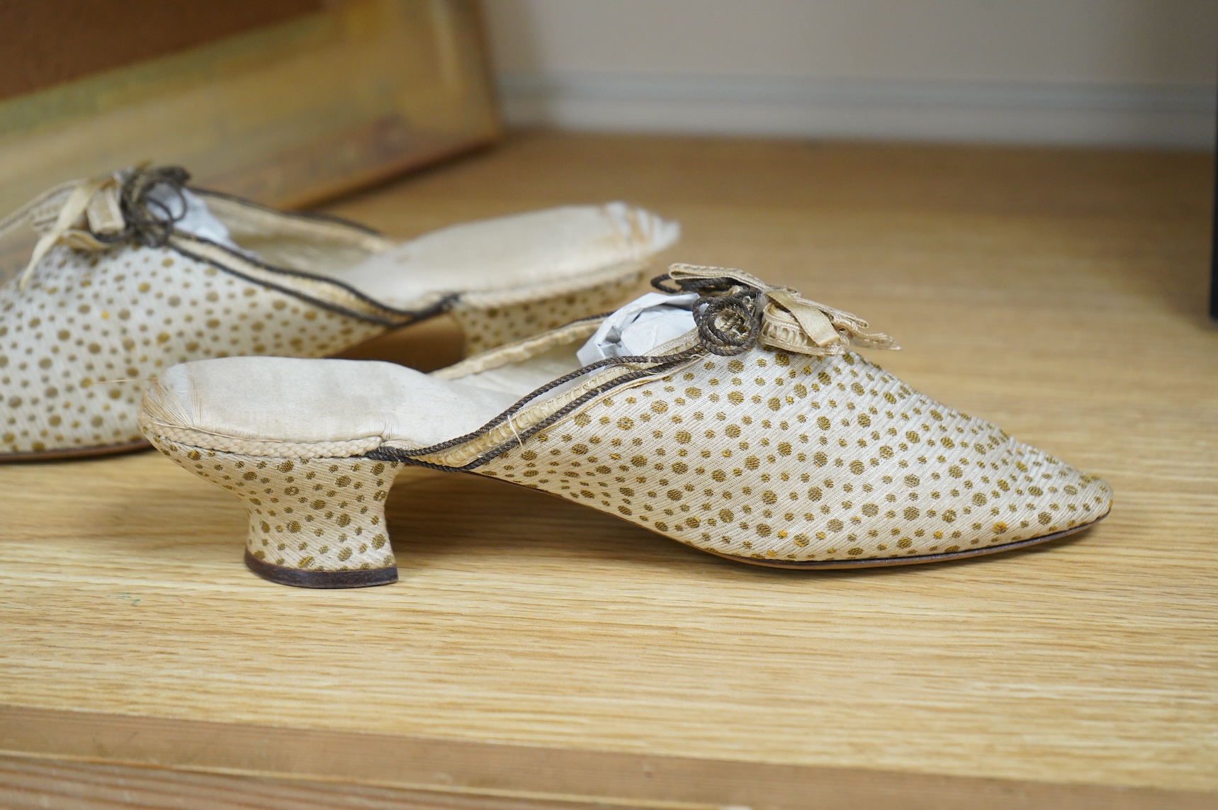 Of interest to collectors and costume designers: a pair of late 19th / early 20th century ladies gold spot embroidered mules, decorated at the front with a rosette of silk ribboning and fine cording. Condition - the cord